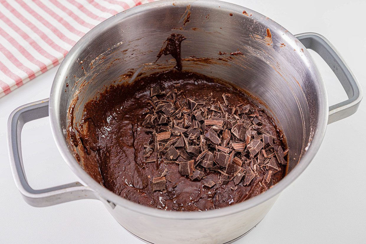 adaugare ciocolata taiata in bucati in compozitia pentru cheesecake brownie reteta pas cu pas